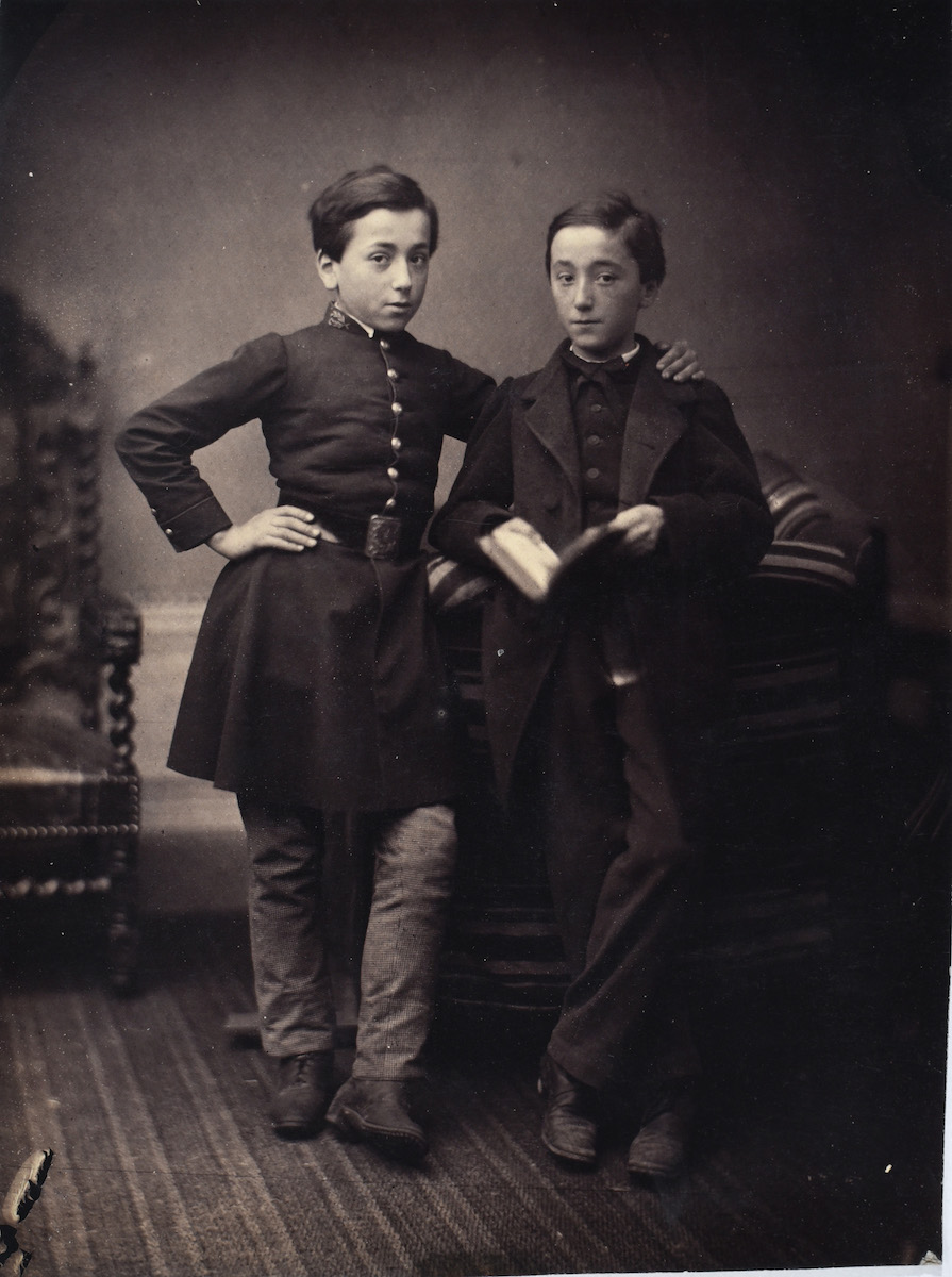 Two Young Boys, One in Military Dress and the Other Holding Book